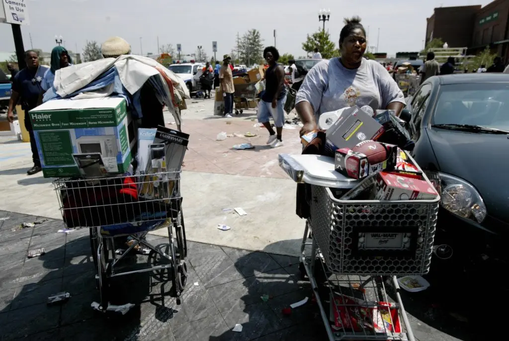 Residents carry out carts of items looted from a local walmart.