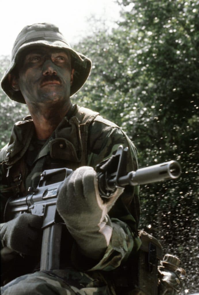 One of combat control team members, armed with a GAU-5 assault rifles, maneuvers down a river by a boat during training. The team members are from the 1st Special Operations Wing.