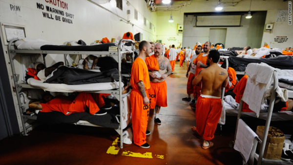 Crowded prison bunk area with lots of inmates