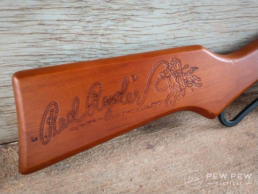 The wood stock of the air rifle is engraved with the classic Red Ryder logo and cowboy image