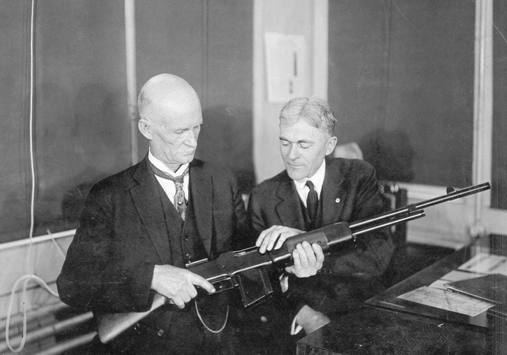 John Moses Browning (left) inspecting a Browning Automatic Rifle (BAR) at the Winchester Repeating Arms Company factory, c. 1918.