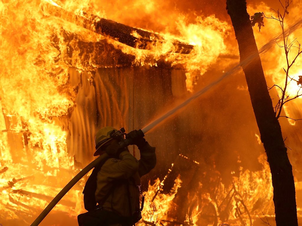 A Cal Fire firefighter monitors a burning home as the Camp Fire moves through the area on Nov. 9.