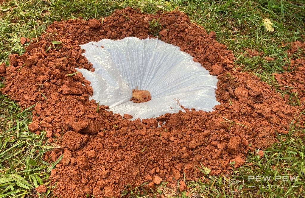 The same hole, with a few rocks weighing down the center of the trash bag and dirty sealing the edges